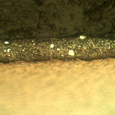 Micrography of the plate section, close to the surface that suffered the impact. The projectile melted and created a film at the surface. HF+HNO3+H2O chemical etch.