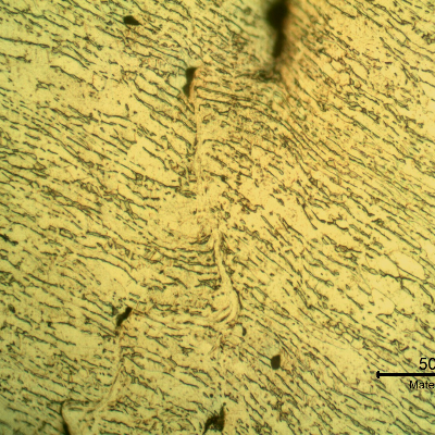 Micrographic detail of the shearing of the material due to the projectile impact.  It is a very localized effect.  HF+HNO3+H2O chemical etch.