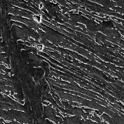 Micrographic detail by SEM of the shearing of the plate due to the projectile impact. It is a very localized effect and that is why the material did not increase the macroscopic hardness level too much. HF+HNO3+H2O chemical etch.