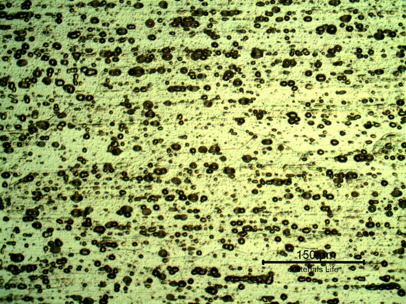 Micrography of the plate in a section, in the middle of the thickness, in a position where the plate was not affected by the shot. The microstructure is granular although the grain boundaries are not resolvable at this magnification.  The black spots are localized corrosion in aligned particles.