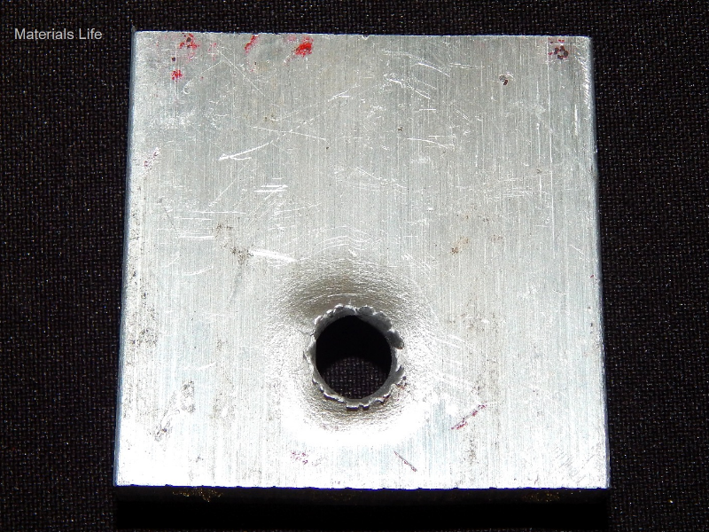 Other view of the 3/8" thickness, 50 mm x 50 mm, 6061 T6 aluminum plate, in the face of impact with the projectile. The plate suffered a localized perforation.