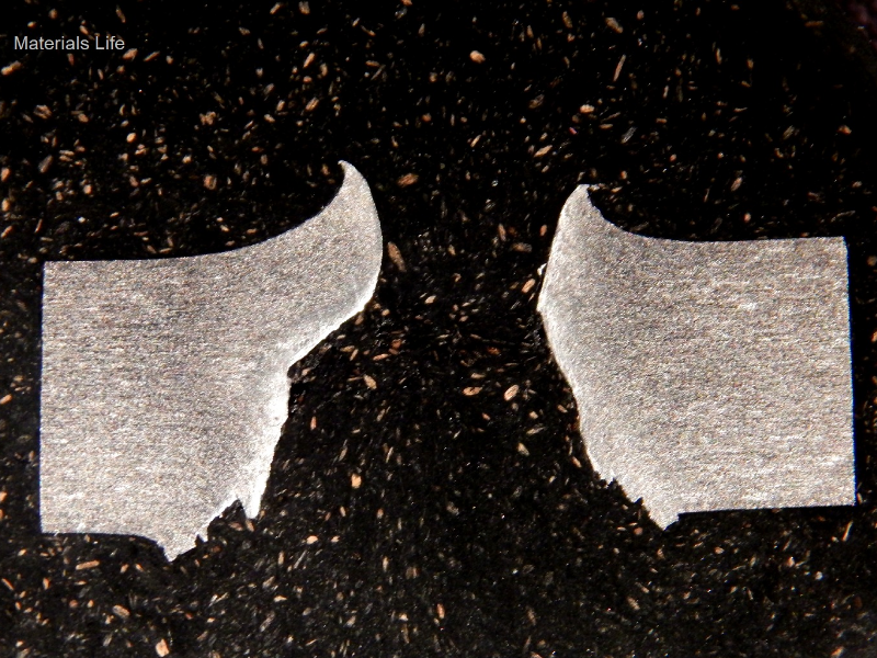 Macrography of the 3/8" thickness aluminum alloy plate, in a section. The side of bullet impact is to the top of the figure. The perforated hole expulsed the material to the top and bottom directions. The hole is larger in the exit of the bullet (to the bottom of the figure).