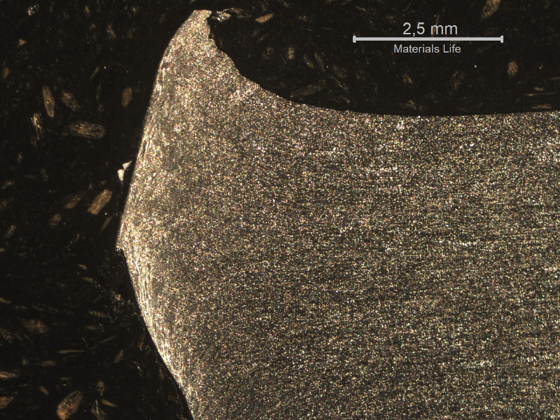 Macrographic detail of the 3/8" aluminum alloy plate. The side of bullet impact is to the top of the figure. The perforated hole expulsed the material to the top and bottom directions. The hole is in the left side of the figure.