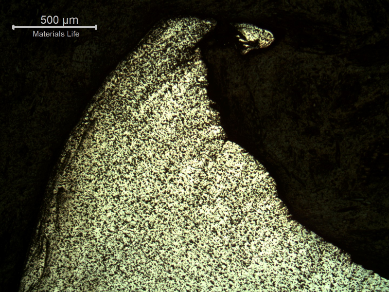 Micrography of the damaged plate at the side of the bullet impact, top of the figure. The perforated hole expulsed the material to the top and bottom directions. There are evidences of plastic deformation of the plate microstructure and the hardness level close to the hole increased from 123 HV to 131 HV (1kg)