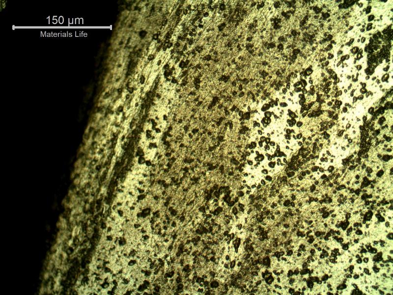 Micrography of the damaged plate at the side of the bullet impact, top of the figure. The perforated hole expulsed the material to the top and bottom directions and the microstructure shows plastic deformation.