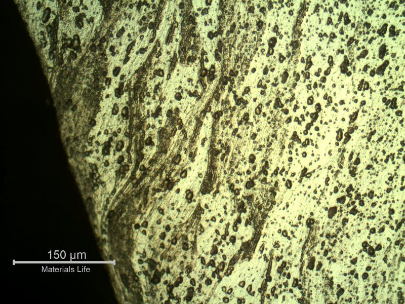Micrography of the damaged plate close to the perforated hole, in the middle of the thickness, showing the strong plastic deformation of the structure, with the grains changing its direction to transverse to the thickness.