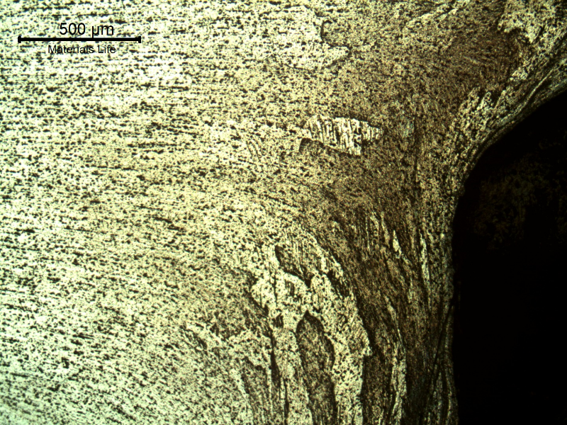 Micrography of the plate at the perforated hole close to the face opposite to the projectile impact (where the bullet exited), showing the strong plastic deformation of the structure.