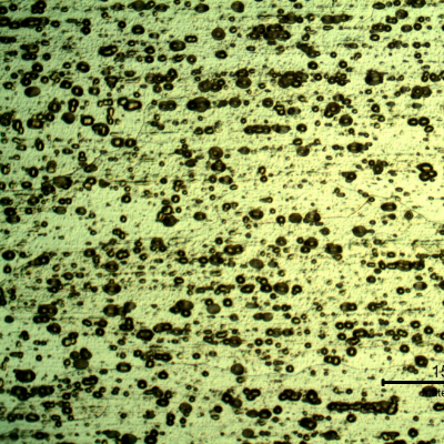 Micrography of the plate in a section, in the middle of the thickness, in a position where the plate was not affected by the shot. The microstructure is granular although the grain boundaries are not resolvable at this magnification. The black spots are localized corrosion in aligned particles.