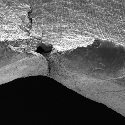 Detail of the margin of the perforated hole in the impact position. It is interesting to observe extreme plastic deformation created by the perforation expulsing the material from the hole, in the direction of the impact.