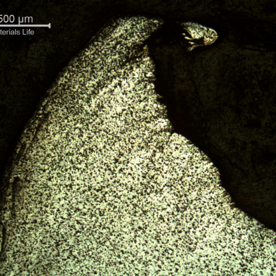 Micrography of the damaged plate at the side of the bullet impact, top of the figure. The perforated hole expulsed the material to the top and bottom directions. There are evidences of plastic deformation of the plate microstructure and the hardness level close to the hole increased from 123 HV to 131 HV (1kg)