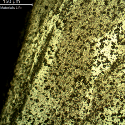Micrography of the damaged plate at the side of the bullet impact, top of the figure. The perforated hole expulsed the material to the top and bottom directions and the microstructure shows plastic deformation.