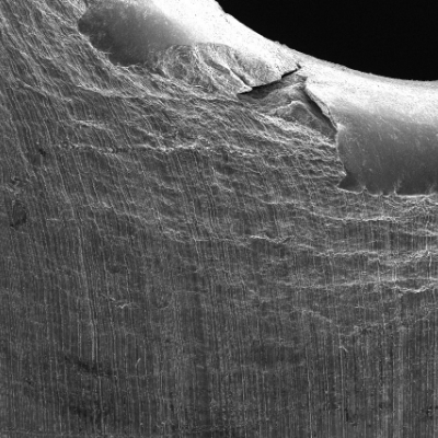 Detail of the margin of the perforated hole in the impact position. It is interesting to observe extreme plastic deformation created by the perforation expulsing the material from the hole, in the direction of the impact.