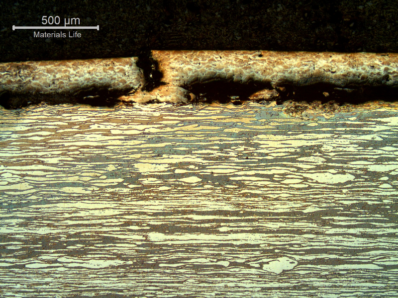 Micrography of a longitudinal section, at the damage surface of the pin, where the thermal spray layer was partially detached and broken. The through layer breaking is ductile, typical of an overloading condition caused by the localized bending of the pin.