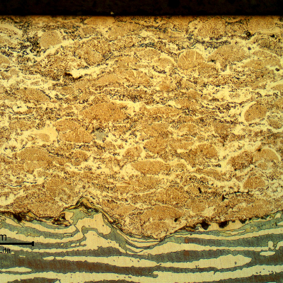 Micrographic detail of a longitudinal section of the pin, at the surface, evidencing the thermal spray layer, about 0.3 mm.  The layer presents typical characteristics of multiple layers, low amount of entrapped oxides and pores.  The interface presents a high roughness level for a good adherence and some entrapped oxides. The structure of the SDSS substrate did not show thermal effects.