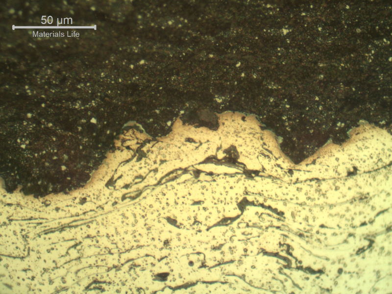 Micrographic detail of the interface between the two thermal spray layers, the first one in stainless steel (bottom of the figure) and the second one, at the surface,in tungsten carbide (top of the figure).  The micrographic sample is etched and that is why the WC is dark (black) and the stainless steel is light (non etched).