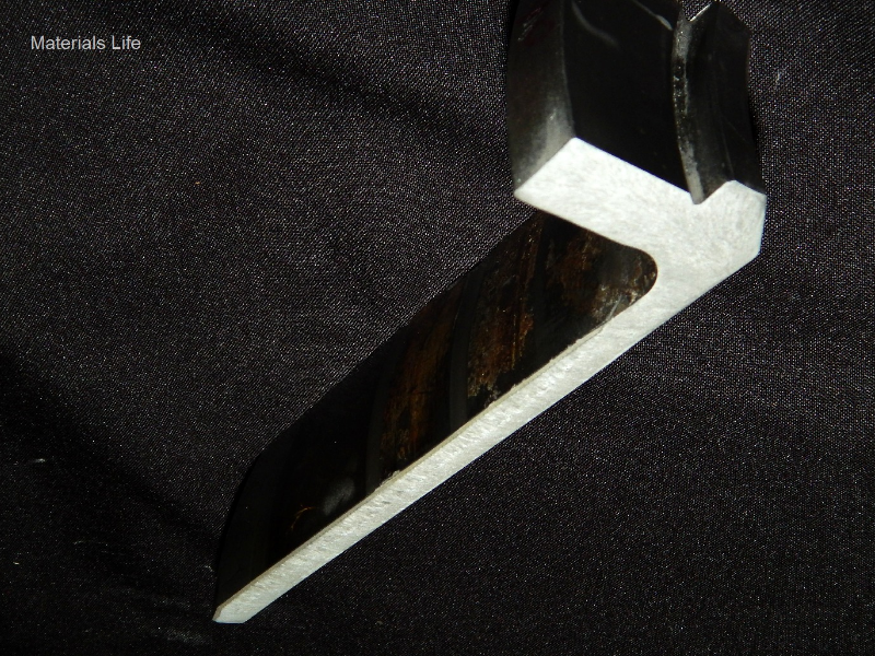 Longitudinal slice of the flanged sleeve, 180 mm long, in a macrography presenting the 1/2" tubular wall thickness where the sealing was applied.  The external surface of the sleeve (seawater wet) is in the left side of the figure and the internal surface (oiled) is in the right side. The flange is to the top of the figure.