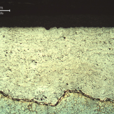 Micrography of a longitudinal section of the sleeve, at the external surface where there are two layers of coating.  The electrolytic etch evidenced the duplex stainless steel substrate (bottom of the figure) and the weave interface of the substrate and the first  thermal spray layer, about 1 mm thick, in a stainless steel. The surface layer, of tugnsten carbide, about 0.2 mm thick,  is black and not clearly visible in this figure.