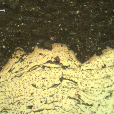 Micrographic detail of the interface between the two thermal spray layers, the first one in stainless steel (bottom of the figure) and the second one, at the surface,in tungsten carbide (top of the figure).  The micrographic sample is etched and that is why the WC is dark (black) and the stainless steel is light (non etched).