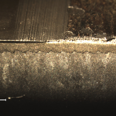 Macroscopic aspect of the OD surface of the sleeve (top of the figure), and a macrography of a longitudinal section (bottom of the figure). In the right side of the figure it is possible to see that the lack of sealing is associated to the detachment of the thermal spray surface layer.