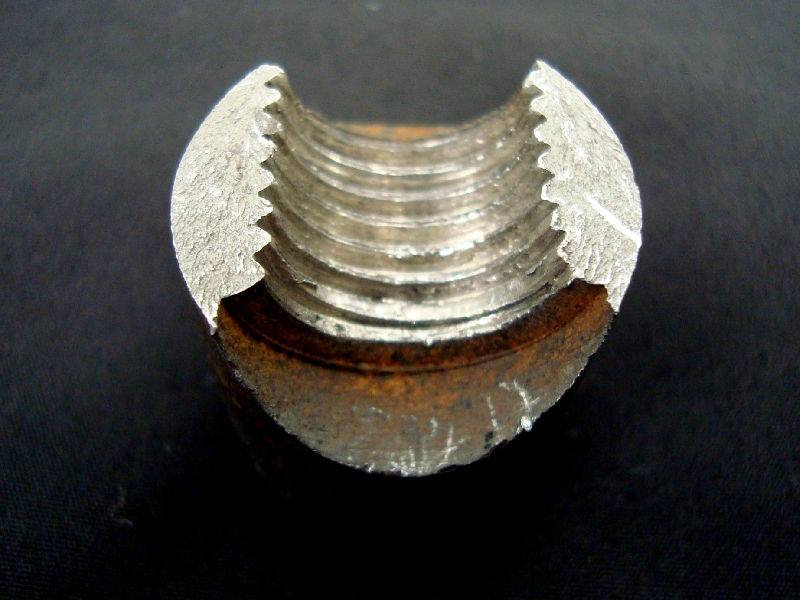 The fracture is flat, in the region of the lower resistant section, presenting no macroscopic evidences of plastic deformation. The starting point of the fracture is indicated by the chevron marks.