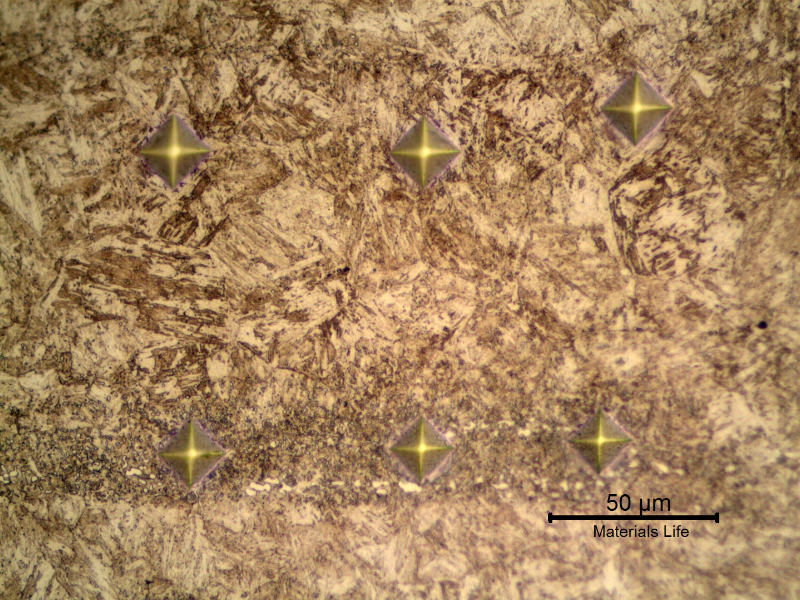Vickers microhardness identations using 100 grams. In a position out of the band (top line). Values from left to right, 380HV; 390HV and 394HV. In a position inside the band (bottom line). Values from left to right, 433HV, 483HV and 473 HV.