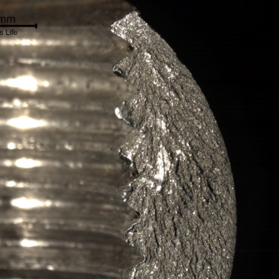 Macroscopically brittle fracture of the barrel nut, starting at the edge of the thread, as shown by the chevron marks.