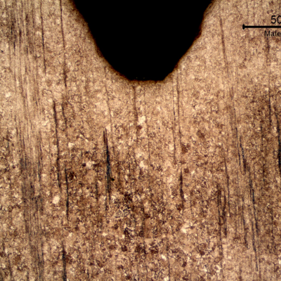 Low magnification micrography of the nut in the longitudinal section, presenting the machined internal thread and a banded microstructure.