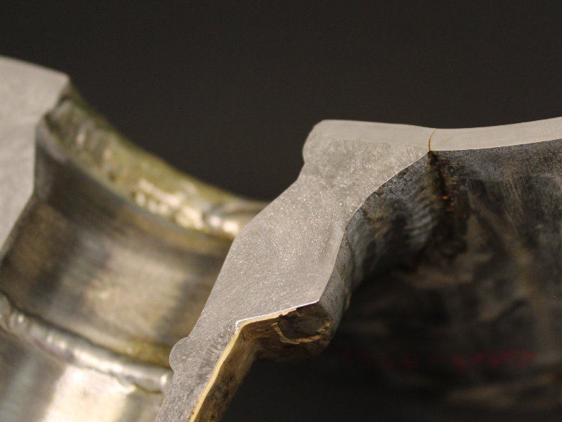 Transverse section of the 14" pipe in the center of the 2" branch using a weldolet fitting welded to the main pipe.  The internal side of the pipe is to the top of the figure and the through wall fatigue cracking is located at the margem of the weld.  It is possible to see that it is a full penetration weld and the fitting thickness is several times larger than the pipe thickness.
