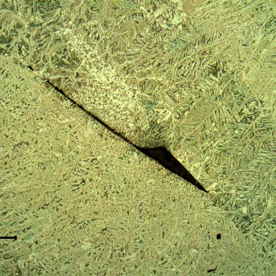 Lack of fusion between passes in the weld metal. This defect is small, probably not detectable in any destructive test and not influencing the failure.