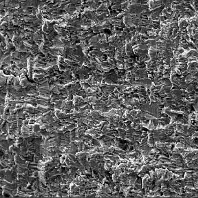 Fracture apperance by scanning electron microscopy in the center of the thickness where the crack propagated through wall. The fracture is flat and the striation is not so clear at this magnification.