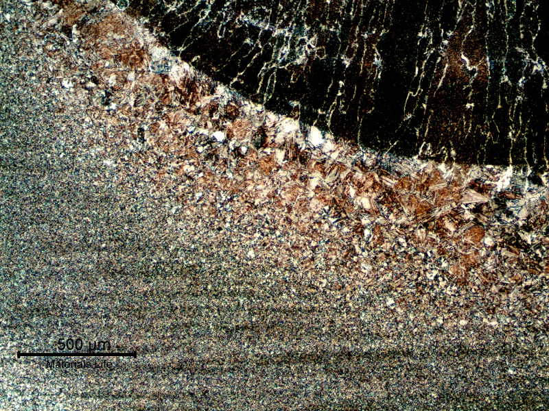 Micrography of the weded joint at the cap pass fusion line. The columnar structure of the weld metal is to the top of the figure; and it is possible to see the coarse grains at the heat affected zone. Both columnar structure and coarse grains are related to the previous austenite grain boundaries. From the fusion line to the base metal (in the bottom of the figure) the grain sizes are refined.