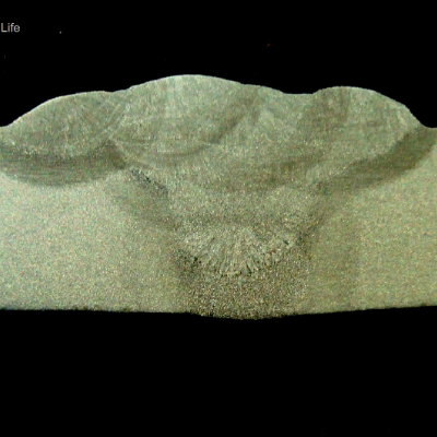 Macrography of a section longitudinal to the pipe and transverse to the weld. The thickness of the pipe is 12,7 mm (1/2") and it was welded in 6 passes, the root pass, one fill pass and four cap passes.