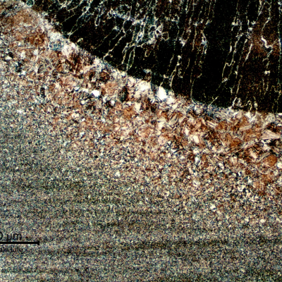 Micrography of the weded joint at the cap pass fusion line. The columnar structure of the weld metal is to the top of the figure; and it is possible to see the coarse grains at the heat affected zone. Both columnar structure and coarse grains are related to the previous austenite grain boundaries. From the fusion line to the base metal (in the bottom of the figure) the grain sizes are refined.