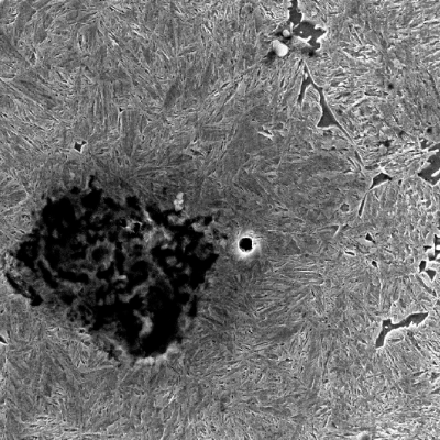 Micrography of the shaft at the surface in a heat treated position.  The graphite nodule is degradating due to temperature and adjacent the microsctructure is martensitic.