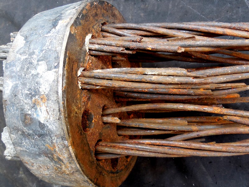 Macro view of individual strand wires emerging from the anchorage fitting, most surfaces covered in reddish-brown corrosion product and several wire ends showing fracture.