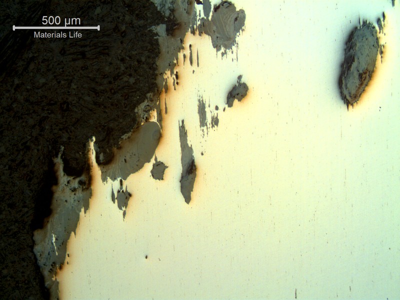 Micrography of a typical corroded wire, in a longitudinal section as polished, showing loss of thickness by corrosion.  The loss of material is accelerated by the corrosion in "layers"  associated to the strained microstructure.