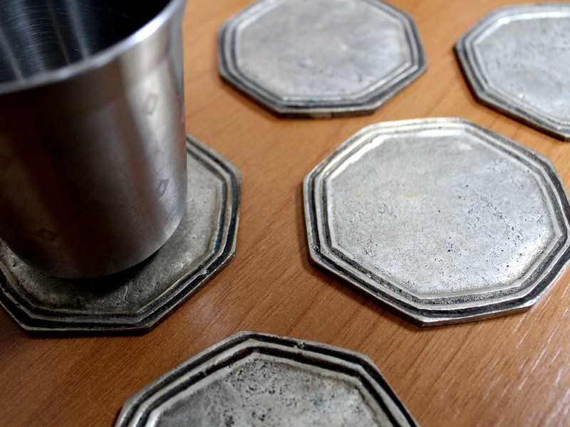 The coasters present a handmake look. The grooves are of different sizes and the octogonal shape is irregular. The pieces presented a weight that suggested that the bright finish is a metallic coating, later identified by EDS analysis as silver coating,  typical of a decorative plating.