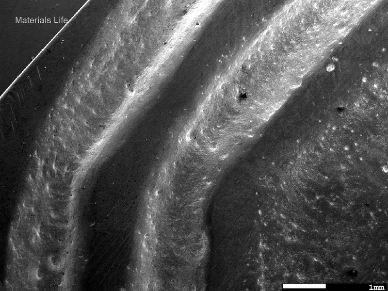 Aspect of the coaster surface grooves, by scanning electron microscopy in a low magnification, showing in the right side the flat region that serves as a support; and in the left side the decorative grooves. The smooth surface in the groove suggests that the coasters were manufactured by casting.