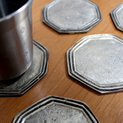 The coasters present a handmake look. The grooves are of different sizes and the octogonal shape is irregular. The pieces presented a weight that suggested that the bright finish is a metallic coating, later identified by EDS analysis as silver coating,  typical of a decorative plating.