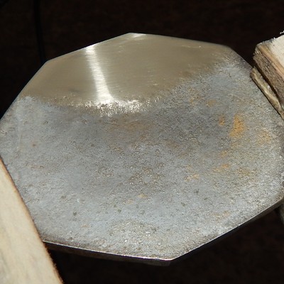 Aspect of the back of the coaster after grinding. The coating was partially removed. The chemical analysis was conducted in the ground part to obtain the composition of the substrate, that showed to be a yellow brass alloy.  It is interesting to note that the alloy presented 2.3% lead.