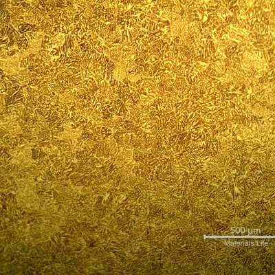 Low magnification metallography of the coaster after etching, revealing a casting structure of alpha plus beta phases.  Beta is the dark brown matrix phase and alpha is the dendritic yellow phase.
