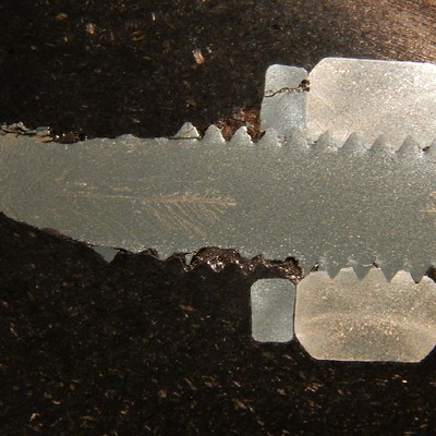 Macrography of the longitudinal section of a fractured bolt, still threaded to the nut and with the lock washer. The cracks can be seen in several positions: in the threads (removing then); in the center of the bolt (branched) and also in the washer (longitudinal branched cracks).