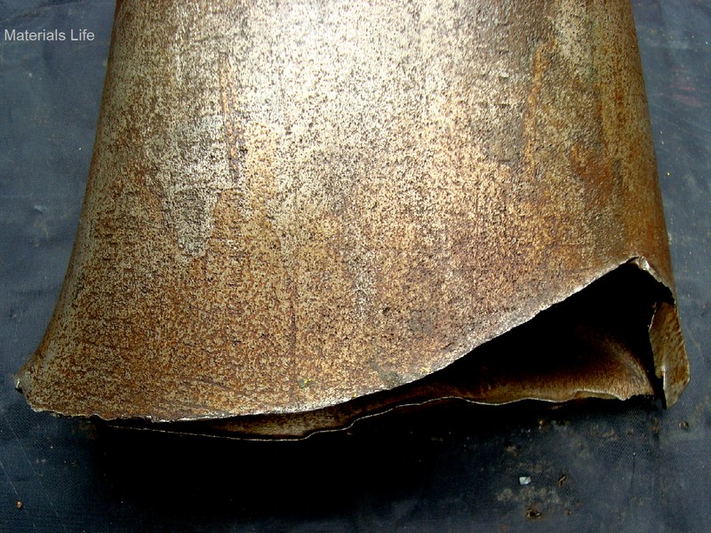 Lateral image of a collapsed API 5D grade S135 drill pipe, presenting the fractured region (bottom of the figure) at the pipe body. Although the pipe steel is of a high strenght, the fracture characteristic is ductile, evidencing strong plastic deformation.