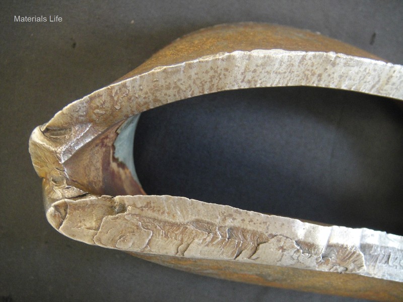 Macroscopic view of the fracture in the pipe body.  In the bottom of the figure, the fracture of the pipe shows a thicker thickness, revealing that this is the pipe region that was first damaged by bending (buckling).  In the top of the figure, the fracture shows a (ductile) shearing mechanism and the thickness is thinner, as will be better observed in the macrography.