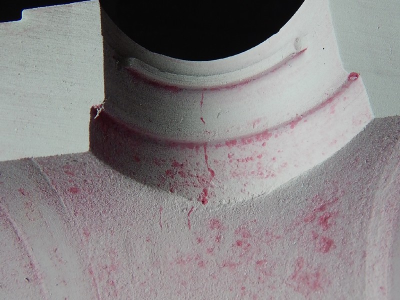 Penetrant test (dye check) image of the cracks at the surface of the actuator hole, viewed from inside of the body after the longitudinal cut.  The aspect of the cracks at the hole, close to the internal side of the valve, is not the same as the aspect of the cracks at the external side (a straigth line), suggesting that the original cracks had propagated by fatigue through wall. The penetrant did not stained too much at the cracked area, indicating that the cracks are not too deep in this position, or are not fully opened to the surface.