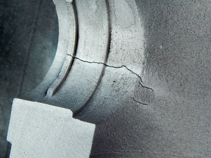 Magnetic particle test of the same cracks at the edge of the actuator hole, viewed from inside of the body.  The cracks appeared more clearly with this test than with the penetrant test, suggesting that the cracks are not fully opened to the surface.
