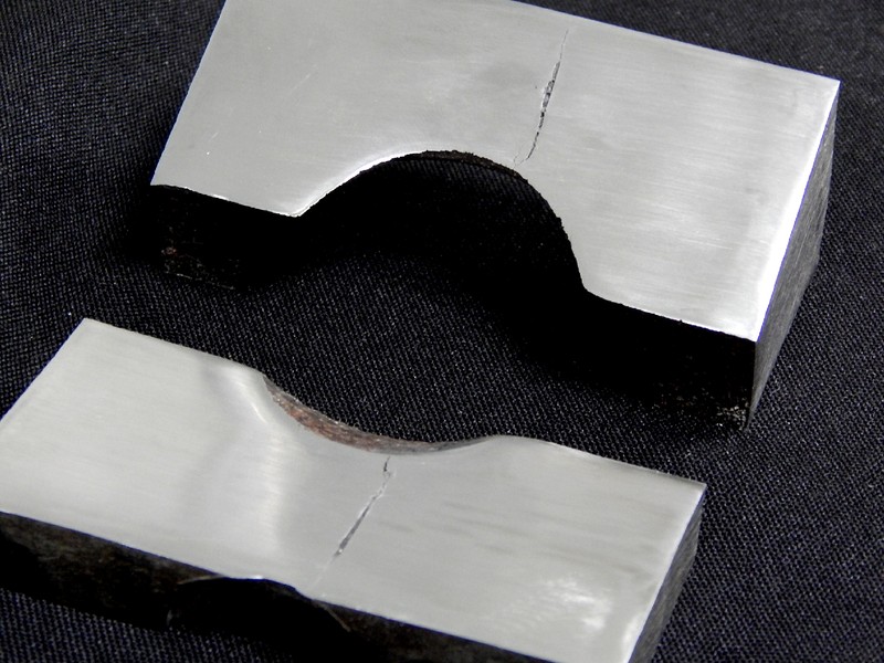 Longitudinal section of the cylindrical body showing two pieces with the cracks, close to the position of the actuator hole.  The valve body thickness is 40 mm at the location where the cracks appeared.