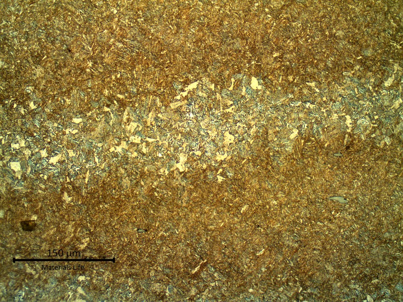 Micrography of a longitudinal section of the valve body presenting a martensitic microstructure.  The structure is banded and the darker regions show inclusions (grey sulfides).