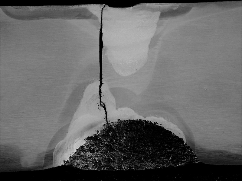 Macrography of the longitudinal section of the valve body, at the cracked position close to the actuator hole.  The valve body is 40 mm thick and at this position it is possible to see that there are two regions where the body was welded, close to the inner surface (bottom) and at the close to the outer surface (top). The through wall crack presented a branch aspect close to the repair in the ID and a straight aspect when propagating from the repair.