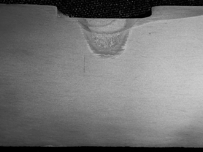 Macrography of the longitudinal section of the valve body, at the cracked position, a little far from the actuator hole.  The valve body is 40 mm thick at this position and it is possible to see that at this position only one region is welded in repair, close to the outer surface (top), and there is a crack, transverse to the thickness, that is difficult to see with this magnification and that is clearly the propagation in fatigue.